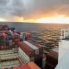 aken from the upper deck of a cargo ship looking over containers and the sunset