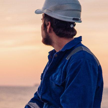 Man wearing a hard hat looking out towards the ocean