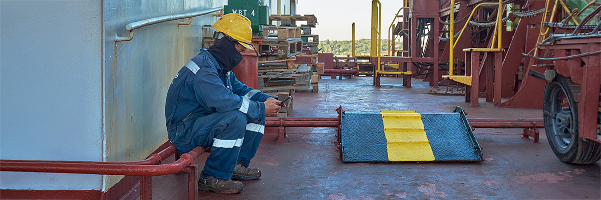 seafarer on ship deck looking at mobile phone 