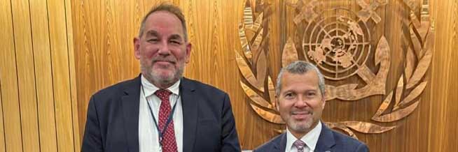 David Anderson (left) and IMO Secretary General, Arsenio Dominguez, in front of wood carving of IMO crest