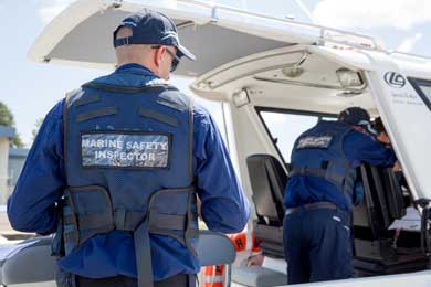 two marine inspectors in dark blue uniforms and caps from behind as they inspect the helm of a boat