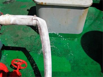 Fire hose that is attached on a ship. It has holes and water is leaking out