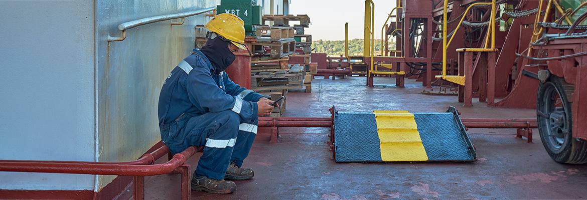 seafarer on ship deck looking at mobile phone 