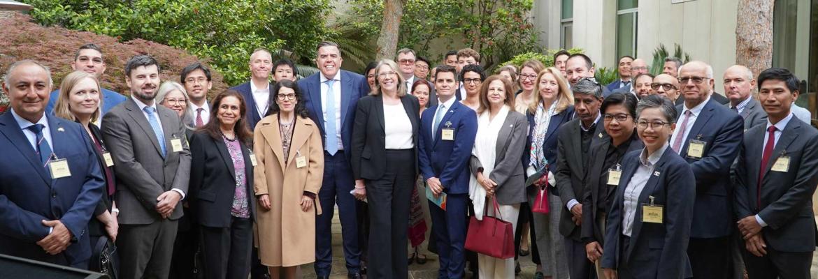 Large group of people smiling in suits in courtyard