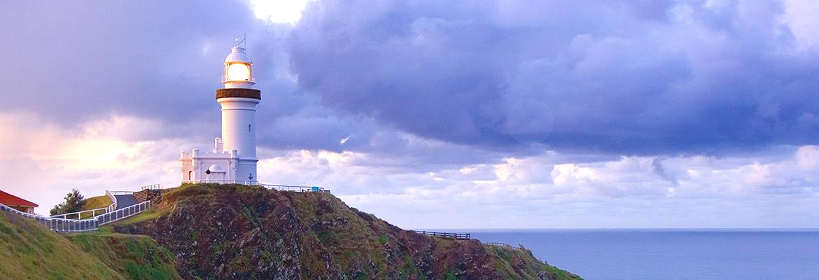 Cape Byron lighthouse looking at the cliff and lighthouse from the ocean during sunset