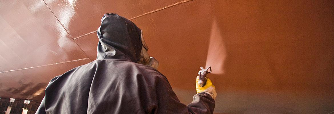 Person in a spray painting suit spraying the hull of a vessel