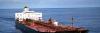 Large oil tanker sailing on calm ocean, viewed from above and behind, with a white superstructure and red deck featuring pipes and equipment.