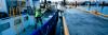 Seafarer in lifejacket handling mooring ropes on a vessel beside the dock.