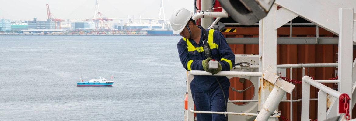 A man in a white hard hat with a controller in his hand looking down